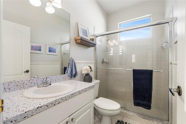 bathroom with toilet, wood walls, tile patterned floors, a shower with shower door, and vanity