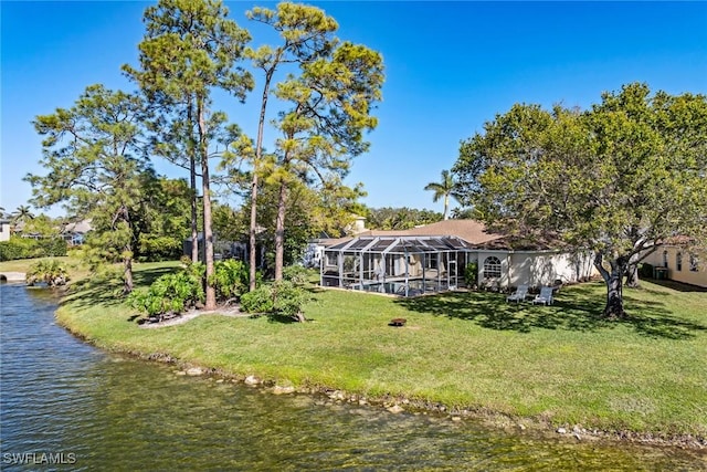 back of house with a lanai, a yard, and a water view