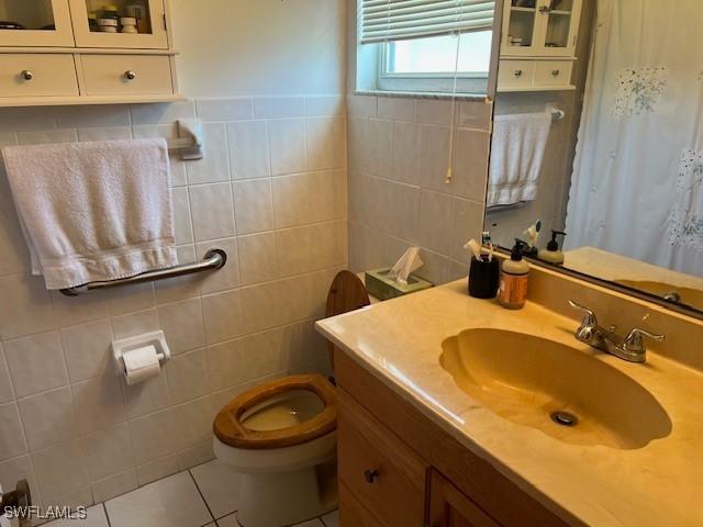 bathroom featuring tile patterned floors, vanity, toilet, and tile walls