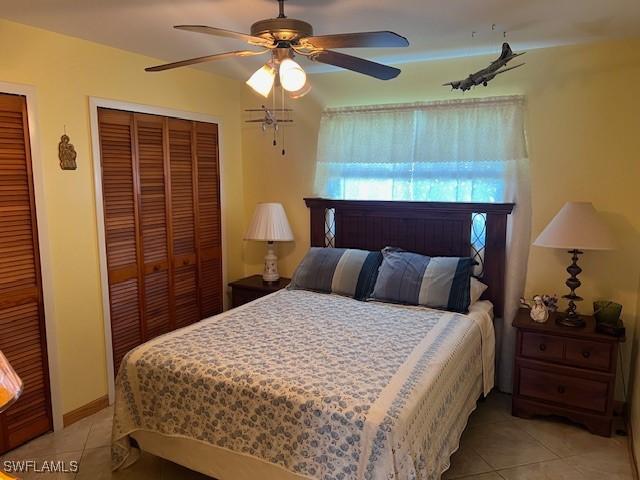 tiled bedroom featuring two closets and ceiling fan