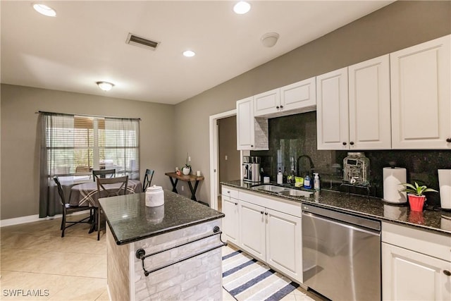 kitchen with dark stone counters, white cabinetry, and stainless steel dishwasher