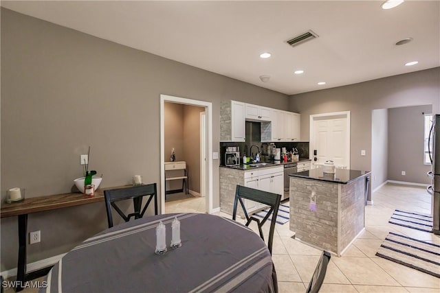 kitchen with a center island, sink, light tile patterned floors, white cabinets, and appliances with stainless steel finishes