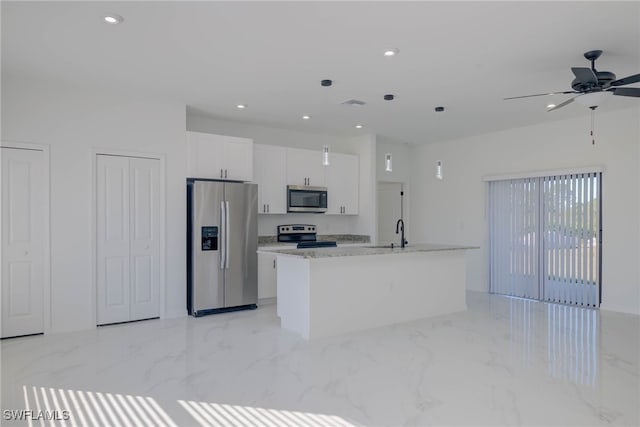 kitchen with white cabinetry, ceiling fan, stainless steel appliances, light stone counters, and a center island with sink