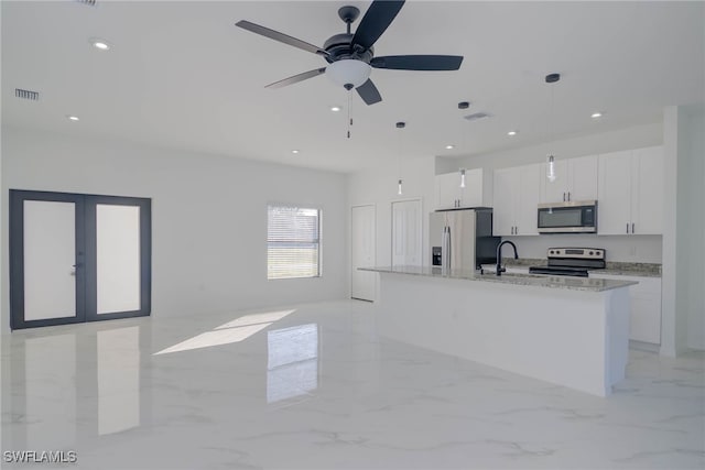 kitchen featuring light stone countertops, stainless steel appliances, pendant lighting, white cabinetry, and an island with sink