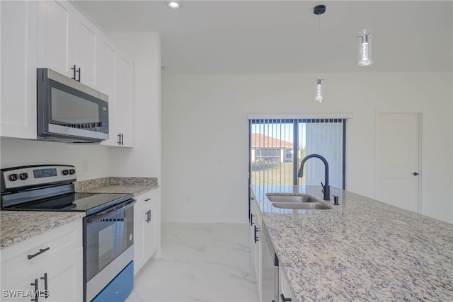 kitchen with white cabinets, appliances with stainless steel finishes, light stone counters, and sink