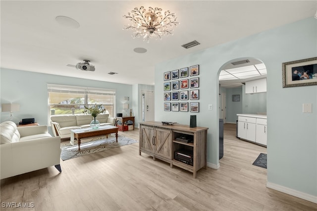 interior space featuring white cabinets, light hardwood / wood-style floors, and a notable chandelier