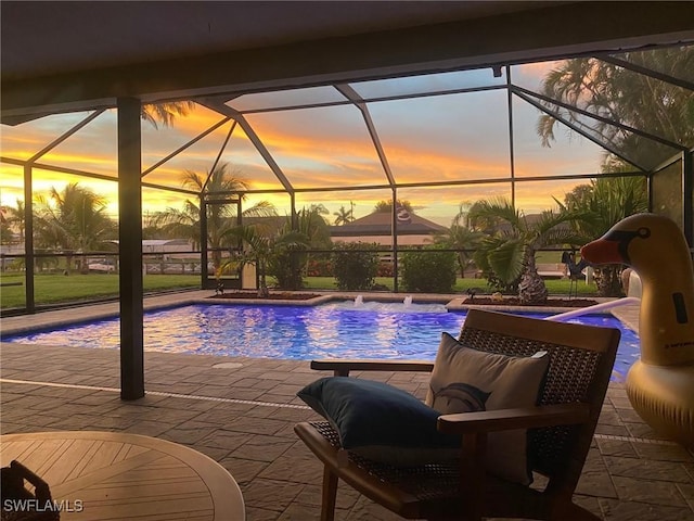 pool at dusk with pool water feature, a patio, and a lanai