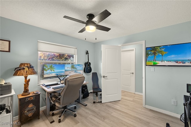 home office featuring ceiling fan, light wood-type flooring, and a textured ceiling