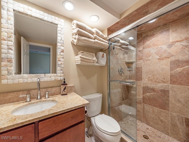 bathroom with toilet, vanity, and a shower with shower door