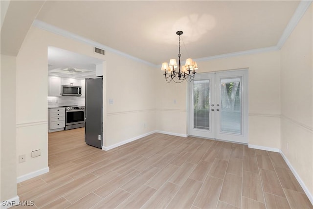 unfurnished dining area with ornamental molding, a notable chandelier, light wood-type flooring, and french doors