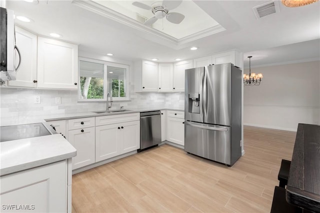 kitchen with appliances with stainless steel finishes, a raised ceiling, sink, and white cabinets