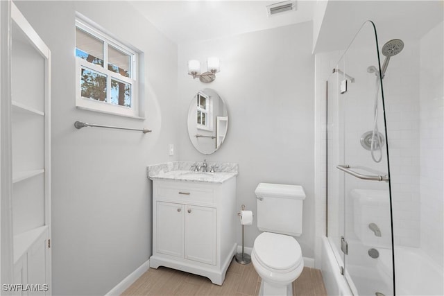 full bathroom featuring vanity, bath / shower combo with glass door, and toilet