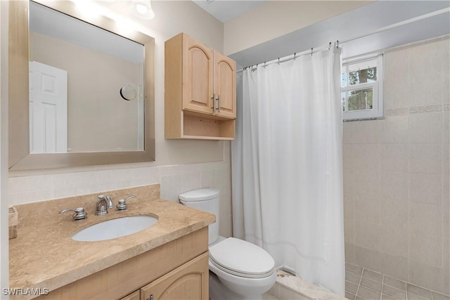 bathroom featuring vanity, toilet, tile walls, and walk in shower