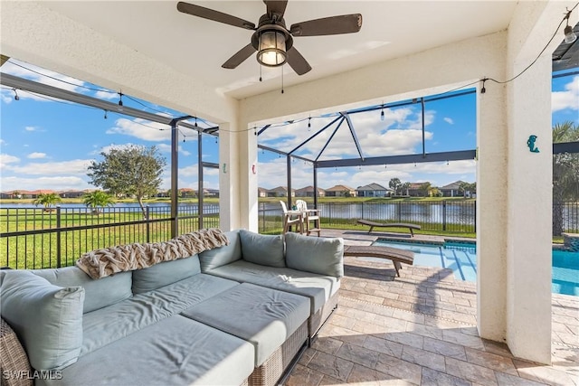 view of patio with an outdoor living space, ceiling fan, a water view, and a fenced in pool