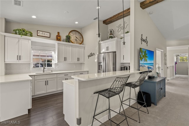 kitchen featuring beamed ceiling, a center island, stainless steel fridge with ice dispenser, and white cabinetry