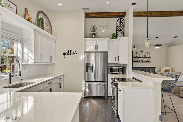 kitchen with backsplash, white cabinets, sink, decorative light fixtures, and stainless steel appliances