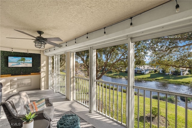 sunroom featuring ceiling fan and a water view