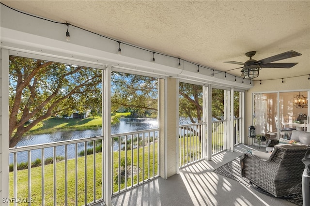 unfurnished sunroom with ceiling fan, a water view, and a wealth of natural light