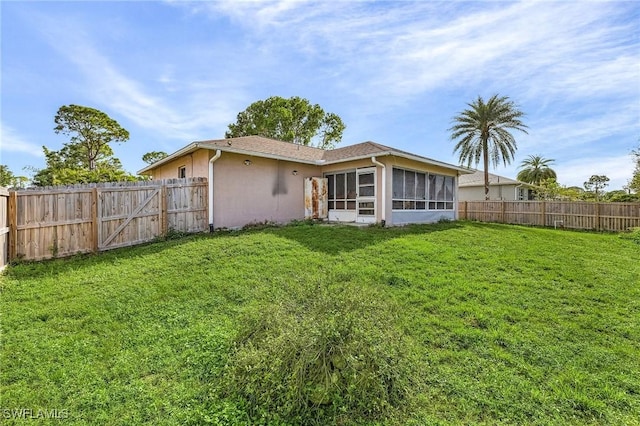 back of property with a sunroom and a yard