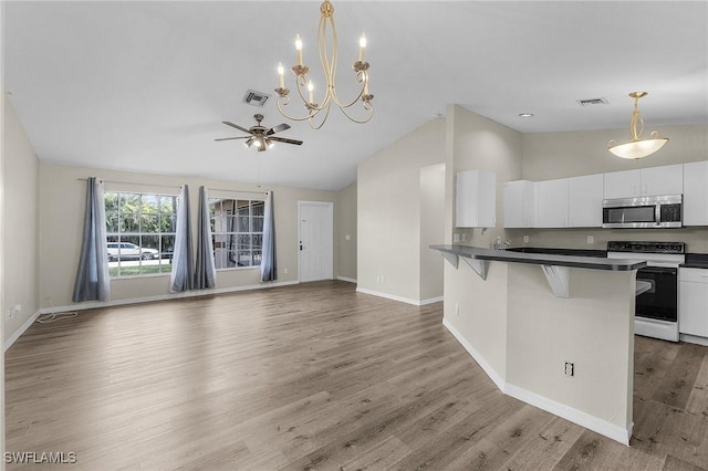 kitchen featuring a kitchen bar, ceiling fan with notable chandelier, white cabinets, white electric range, and hanging light fixtures