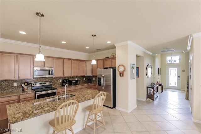 kitchen featuring hanging light fixtures, light tile patterned floors, appliances with stainless steel finishes, tasteful backsplash, and a breakfast bar area