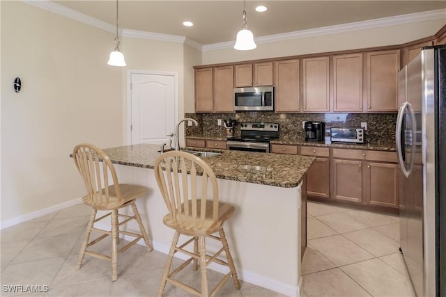 kitchen featuring pendant lighting, a kitchen island with sink, sink, a breakfast bar area, and stainless steel appliances