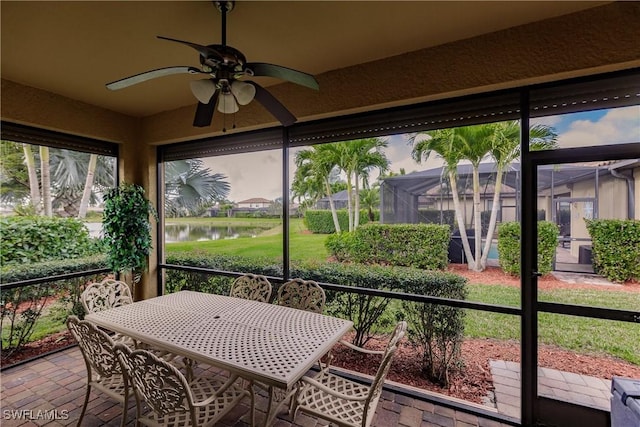 sunroom with a water view and ceiling fan