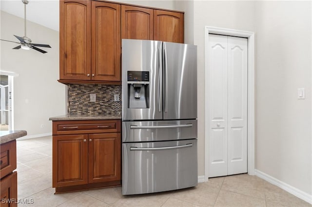 kitchen featuring ceiling fan, backsplash, stainless steel fridge, stone countertops, and light tile patterned flooring