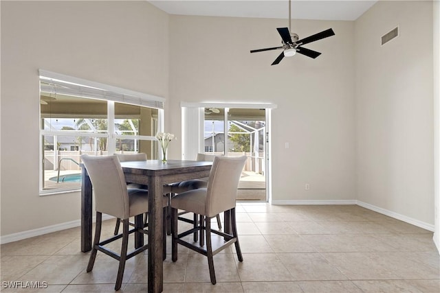 dining room with ceiling fan, light tile patterned flooring, and a towering ceiling