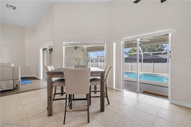 tiled dining area with ceiling fan and a high ceiling