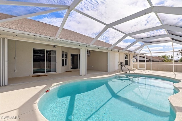 view of pool featuring a patio, glass enclosure, and ceiling fan