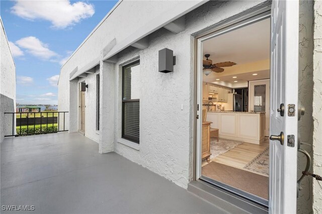 view of exterior entry with stucco siding and a balcony