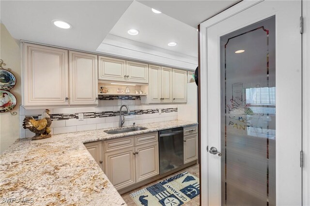 kitchen with sink, black dishwasher, light stone counters, tasteful backsplash, and cream cabinetry