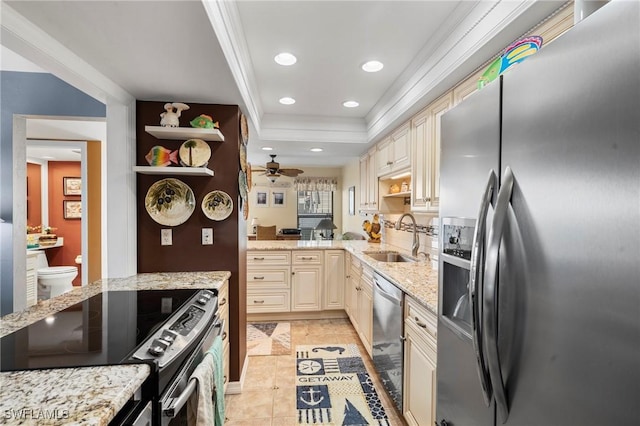 kitchen with appliances with stainless steel finishes, sink, a raised ceiling, light stone countertops, and cream cabinetry