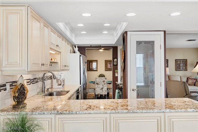 kitchen featuring sink, light stone counters, ornamental molding, decorative backsplash, and cream cabinetry