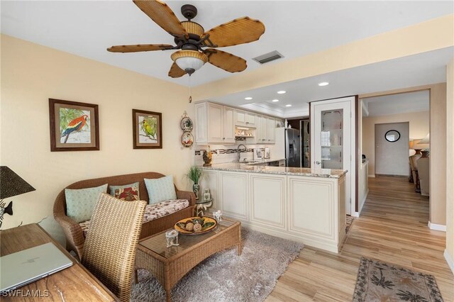 living room featuring sink, ceiling fan, and light hardwood / wood-style flooring