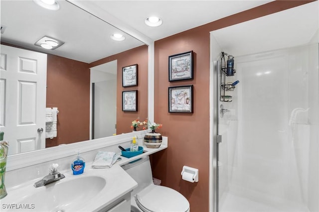 bathroom featuring toilet, vanity, and a shower with shower door