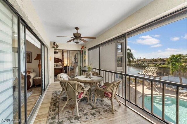 sunroom featuring ceiling fan and a water view