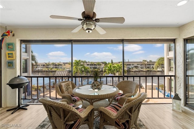 sunroom / solarium with a wealth of natural light, ceiling fan, and a water view