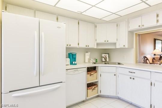 kitchen featuring white cabinetry, sink, light tile patterned floors, and white appliances