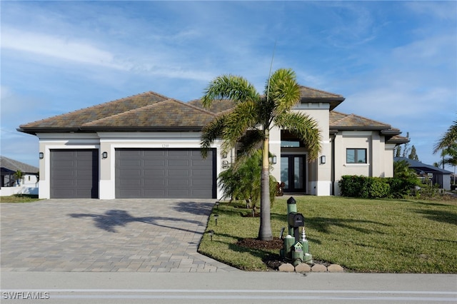 view of front facade with a garage, a front yard, and french doors