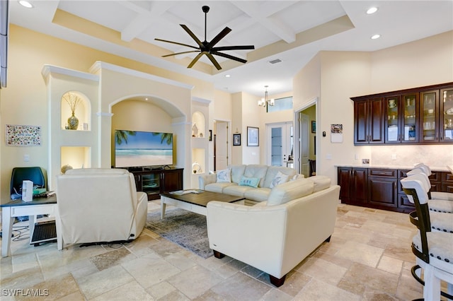 living room featuring ceiling fan with notable chandelier, beamed ceiling, a towering ceiling, and coffered ceiling