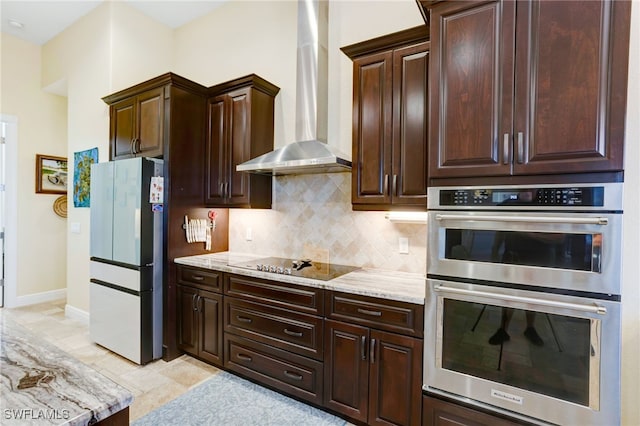 kitchen featuring refrigerator, wall chimney range hood, black electric stovetop, dark brown cabinetry, and stainless steel double oven