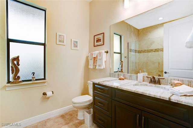 bathroom with vanity, toilet, and tiled shower