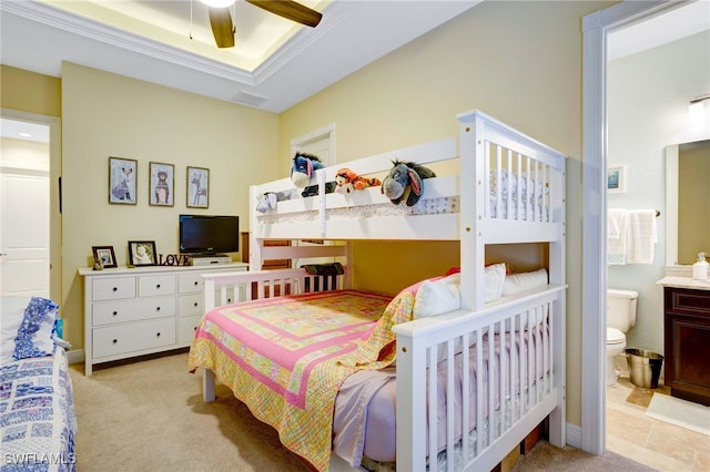 carpeted bedroom featuring ceiling fan, a raised ceiling, and ensuite bath