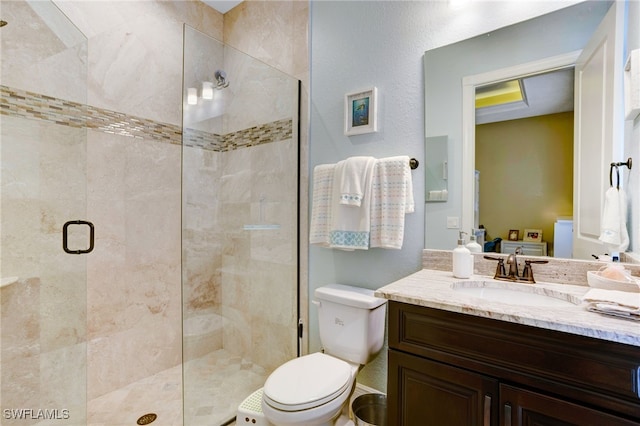 bathroom featuring a shower with shower door, toilet, and vanity