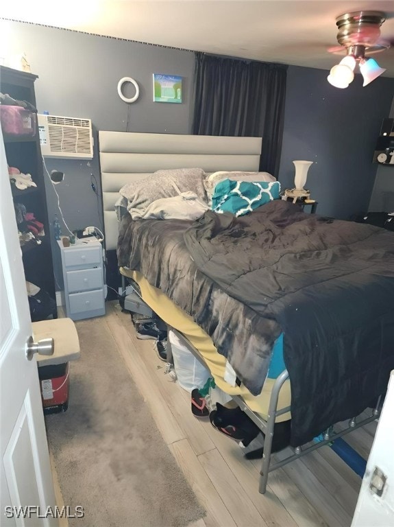 bedroom featuring a wall mounted air conditioner, ceiling fan, and hardwood / wood-style floors