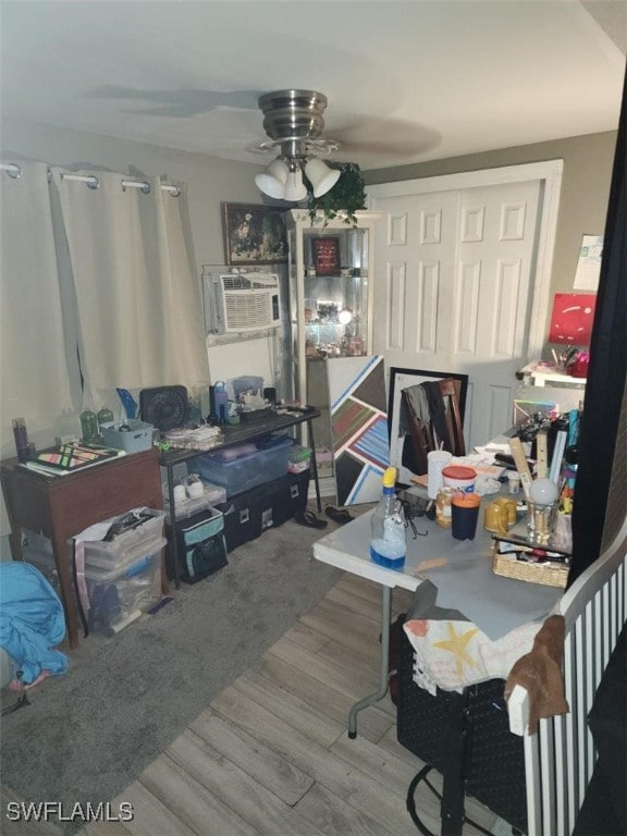 home office featuring hardwood / wood-style floors, ceiling fan, and a wall mounted AC