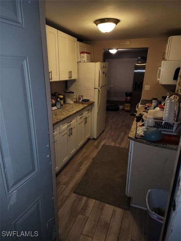 kitchen featuring light stone counters, white appliances, white cabinets, and dark hardwood / wood-style floors