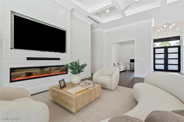 living room featuring hardwood / wood-style floors, a fireplace, ornamental molding, coffered ceiling, and beam ceiling